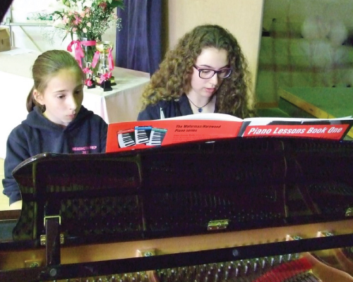 two girls playing piano